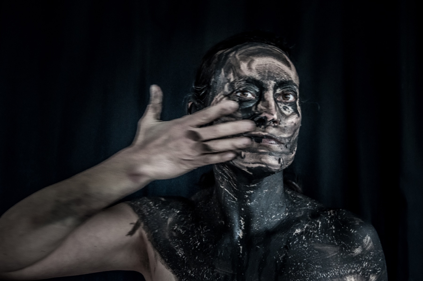 Still from Dis-appear: hand crossing the painted face
