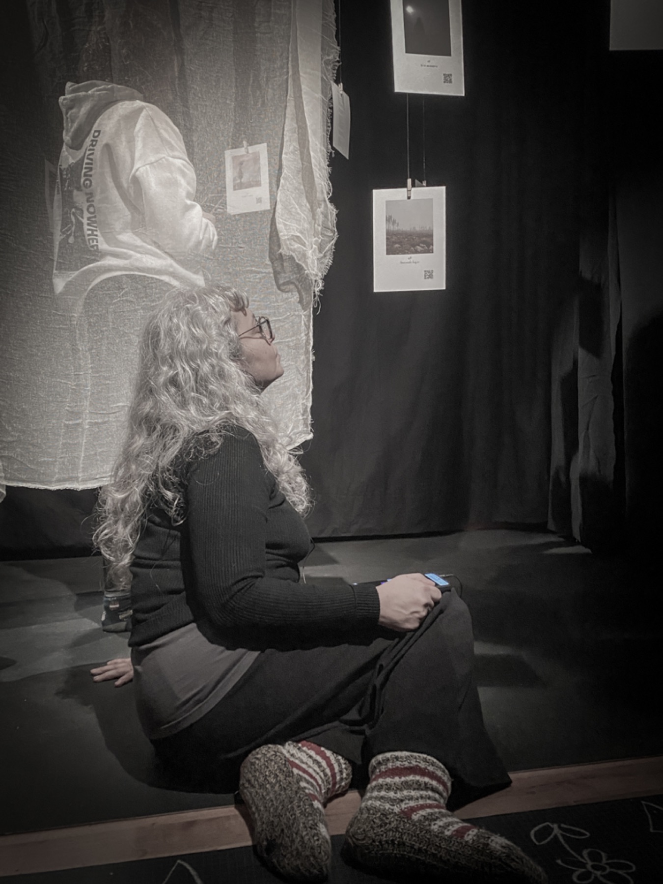 A visitor seated among suspended images and sound